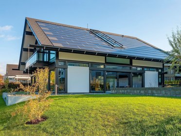 Freistehendes modernes Haus mit großen Fenstern und grünem Rasen