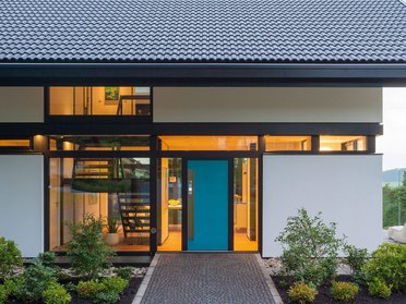 Eingang eines modernen Hauses mit Glasfront und Grünanlagen