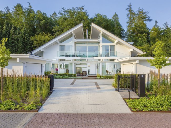 Ansicht einer eleganten Villa mit gläserner Fassade und Garten