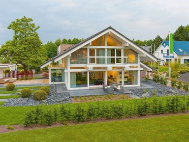 Helles modernes Haus mit großen Fenstern und gepflegtem Garten