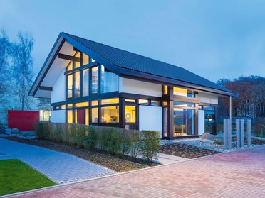 Einfamilienhaus mit großen Fenstern und stilvollem Design in der Dämmerung