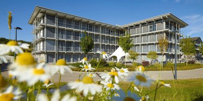 Bürogebäude HUF umgeben von Blumen und blauem Himmel