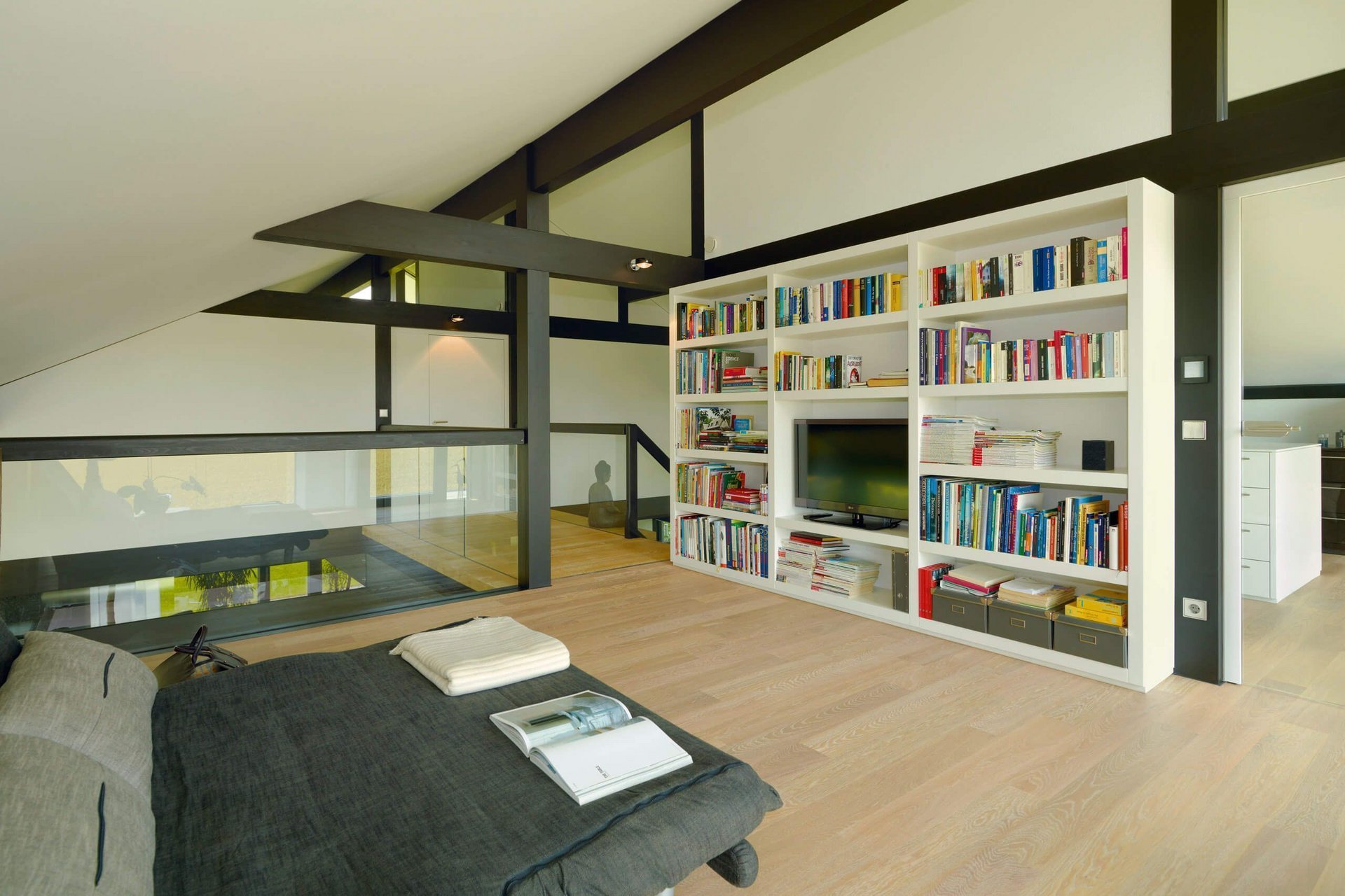 Modernes Wohnzimmer mit Bücherregal und Schlafbereich Geräumiges, helles Zimmer mit moderner Einrichtung und Bücherregal