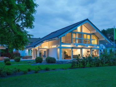 Elegantes Haus mit großen Fenstern und schöner Gartenlandschaft