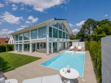 Außenansicht eines modernen HUF Hauses mit Schwimmbad und grünem Garten