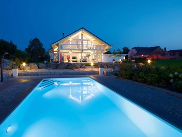 Fachwerkhaus HUF HAUS ART 4 bei Nacht Moderne Architektur mit Swimmingpool und Gartenbeleuchtung