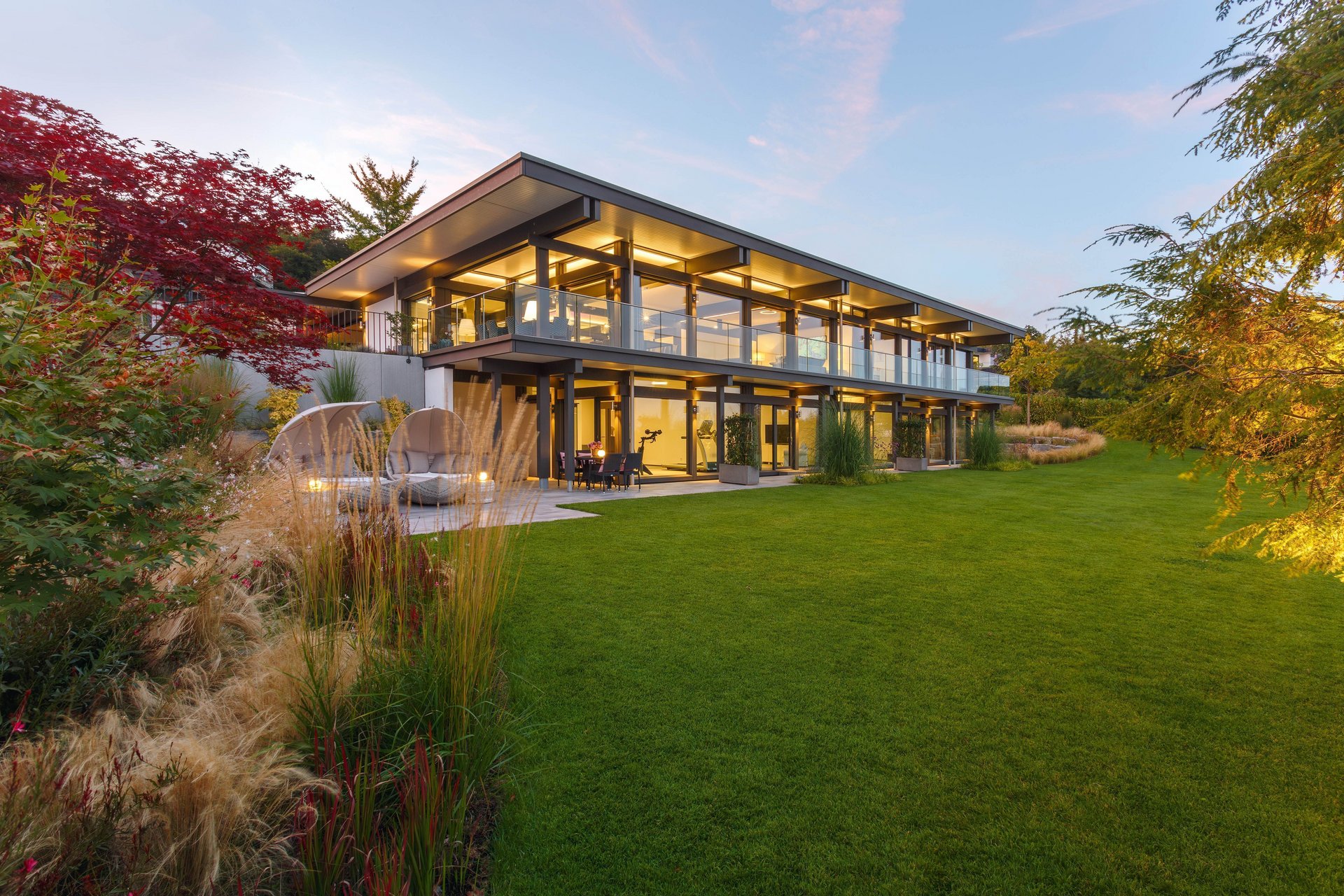 Transparente Architektur des HUF HAUS mit Flachdach und grüner Umgebung