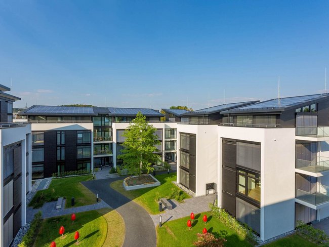 Ansicht des HUF Bürogebäudes mit grüner Landschaft und Solarpanelen