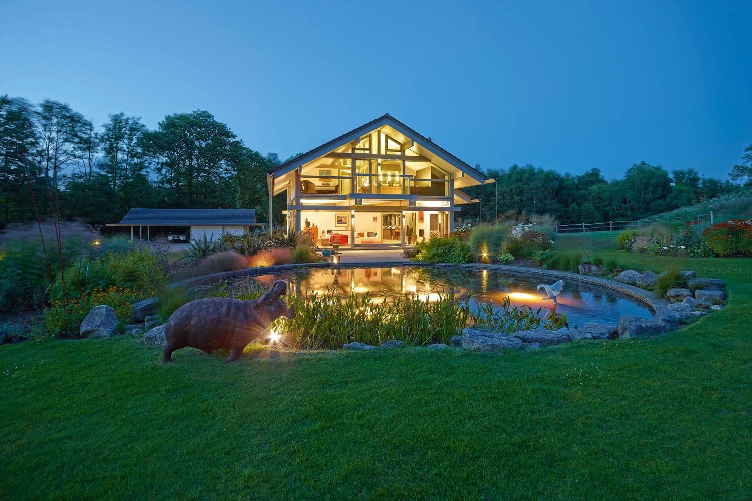 Designhaus mit Garten und Wasserstelle bei Abendlicht