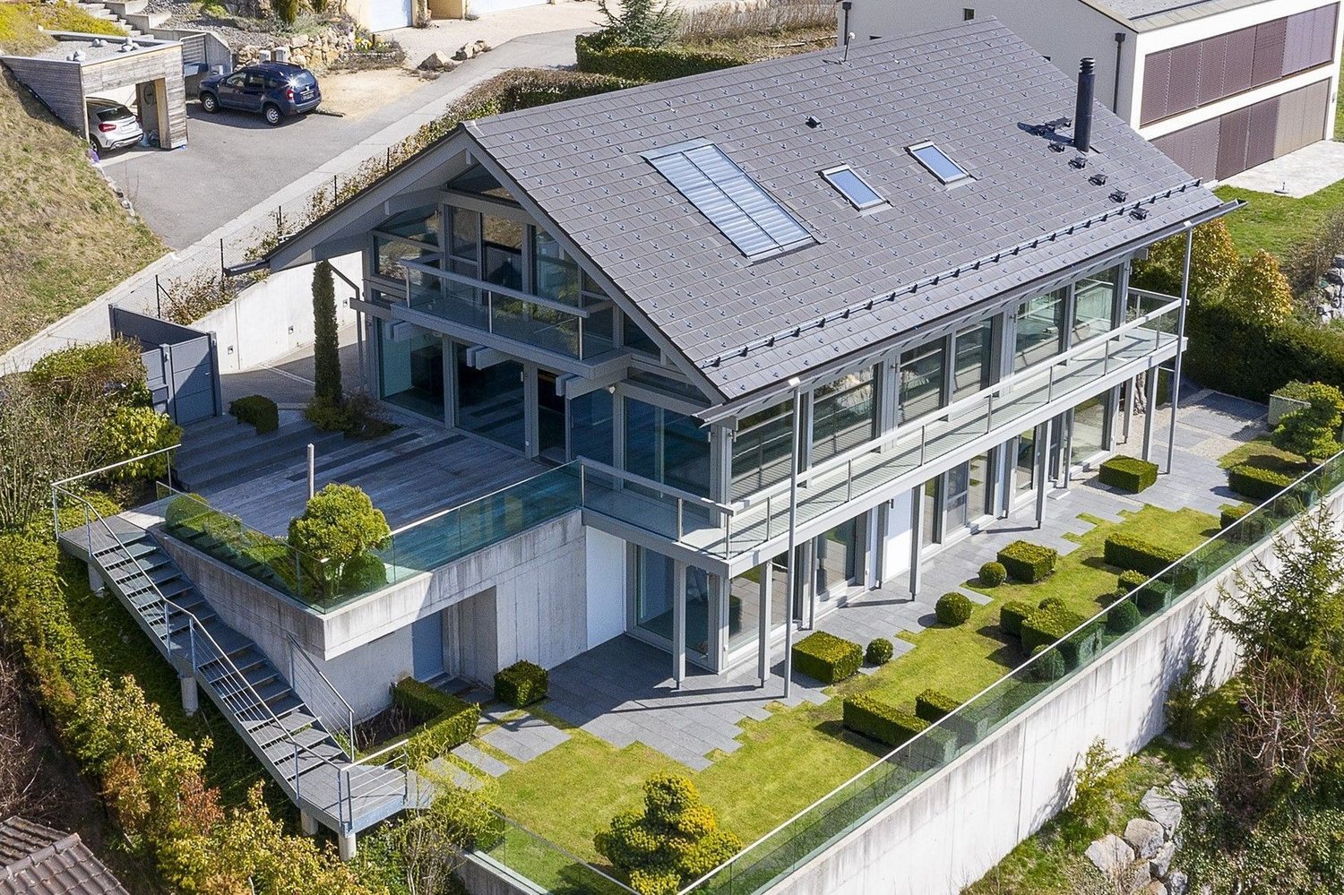 Luftaufnahme eines Hauses mit Glasfront und schönem Garten