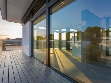 Terrasse mit Glasfront und Blick auf die Stadt bei Sonnenuntergang