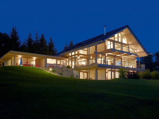 Exklusives HUF HAUS in modernem Fachwerkstil Energieeffizientes Architektenhaus mit großzügigen Glasflächen bei Nacht