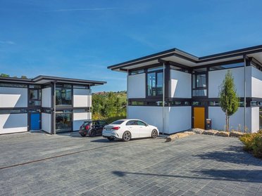 Moderne Architektur mit Glas und Holz, Parkplatz im Vordergrund