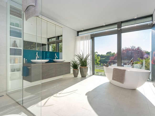Modernes Badezimmer mit freistehender Badewanne Helles Badezimmer mit großen Fenstern und Pflanzen im Inneren