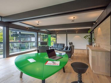 Innenansicht eines modernen HUF Hauses mit grünem Tisch und Bürobereich