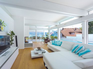 Helles Wohnzimmer mit Blick auf Landschaft und See durch große Fenster