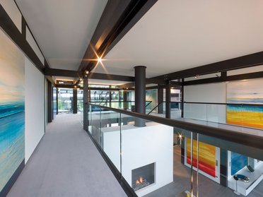 Helle Galerie mit Glasgeländer und modernen Gemälden im Hintergrund.