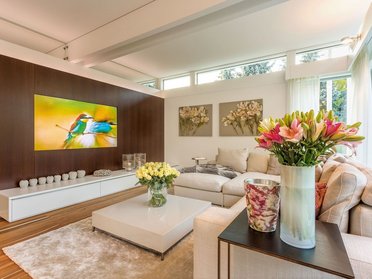 Gemütliches Wohnzimmer mit Sofa, Blumen und Fernseher