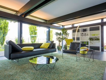 Helles Wohnzimmer mit Sofa, Teppich und großen Fenstern