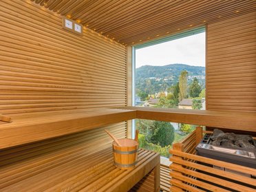 Innensicht einer privaten Sauna mit Holzregalen und Fenster