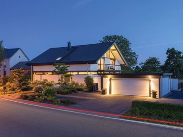 Moderne Architektur bei Nacht mit beleuchtetem Haus Elegantes modernes Haus mit Glas-Elementen und schönen Gärten