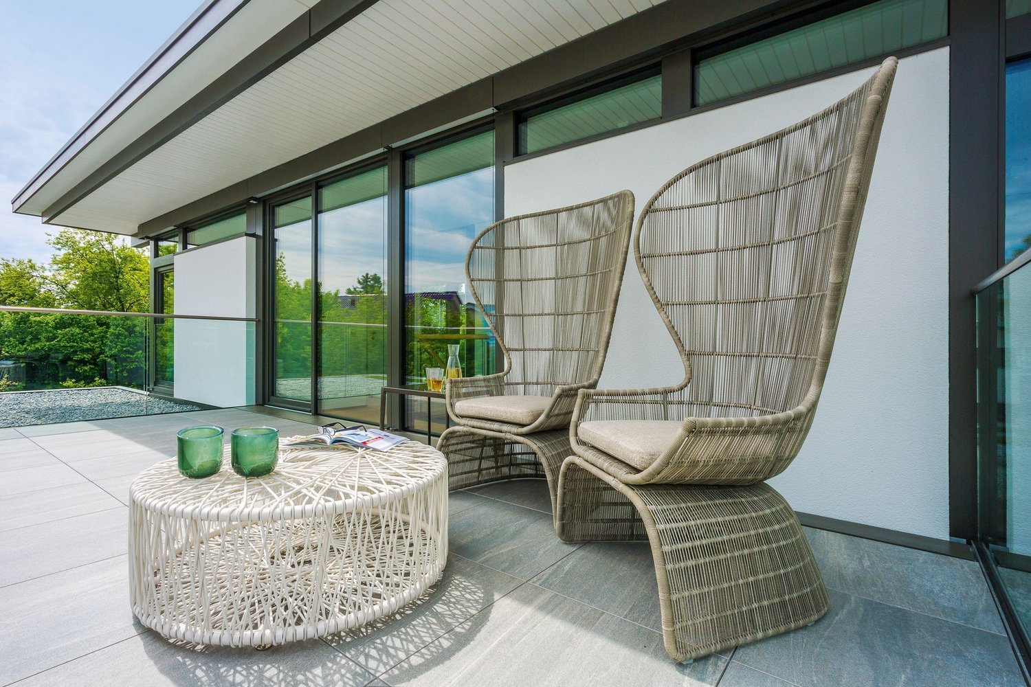 Zwei elegante Stühle und ein runder Tisch auf einer Terrasse