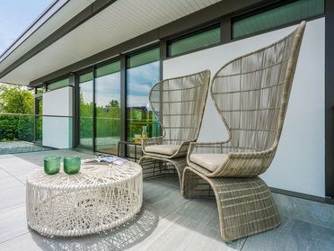 Zwei elegante Stühle und ein runder Tisch auf einer Terrasse
