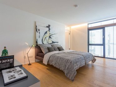 Modernes Schlafzimmer mit Kunstwerk, Holzfußboden und Glasfenstern