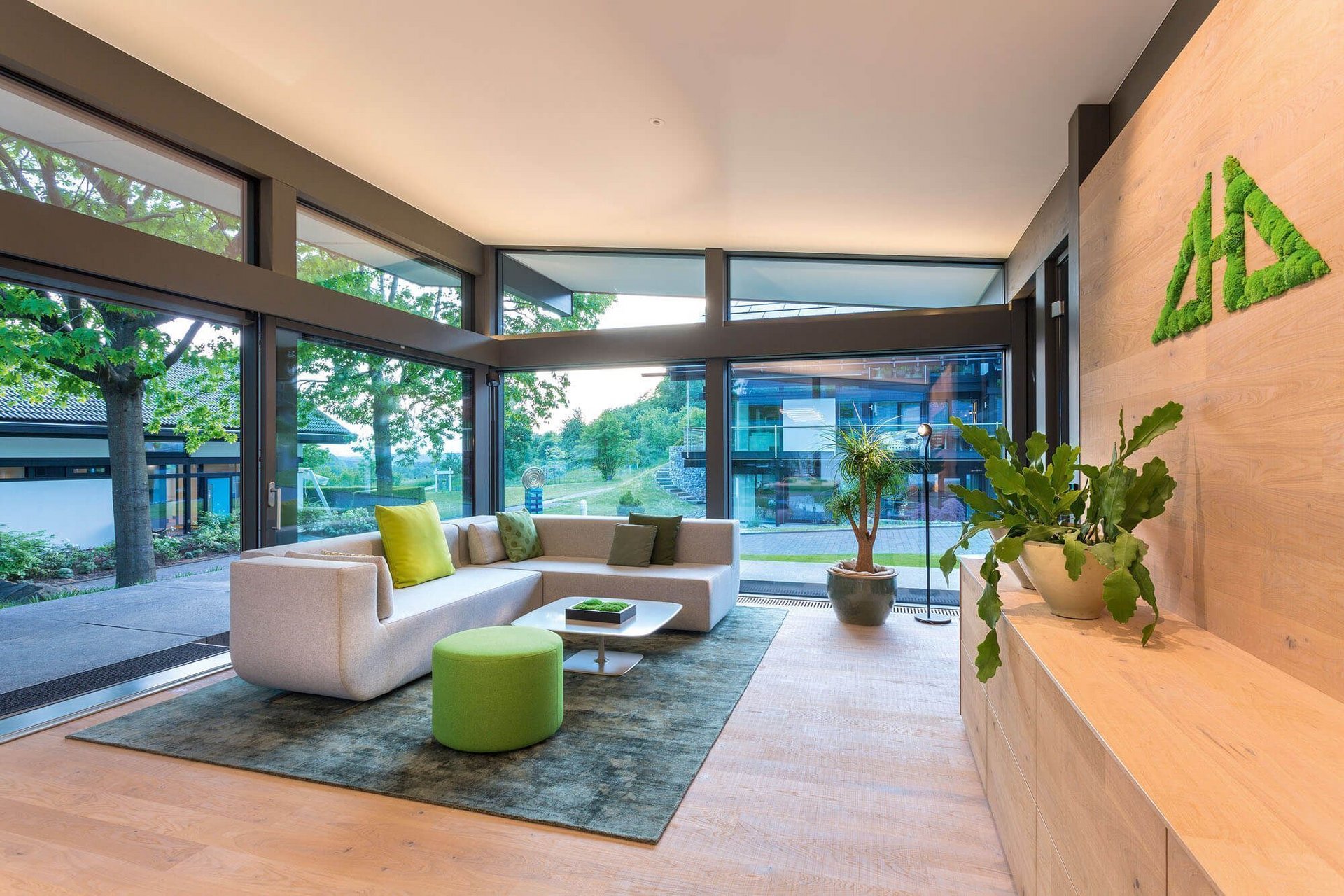 Modernes Wohnzimmer mit viel Licht und Pflanzen Helles Wohnzimmer mit Sofa, Pflanzen und großen Fenstern