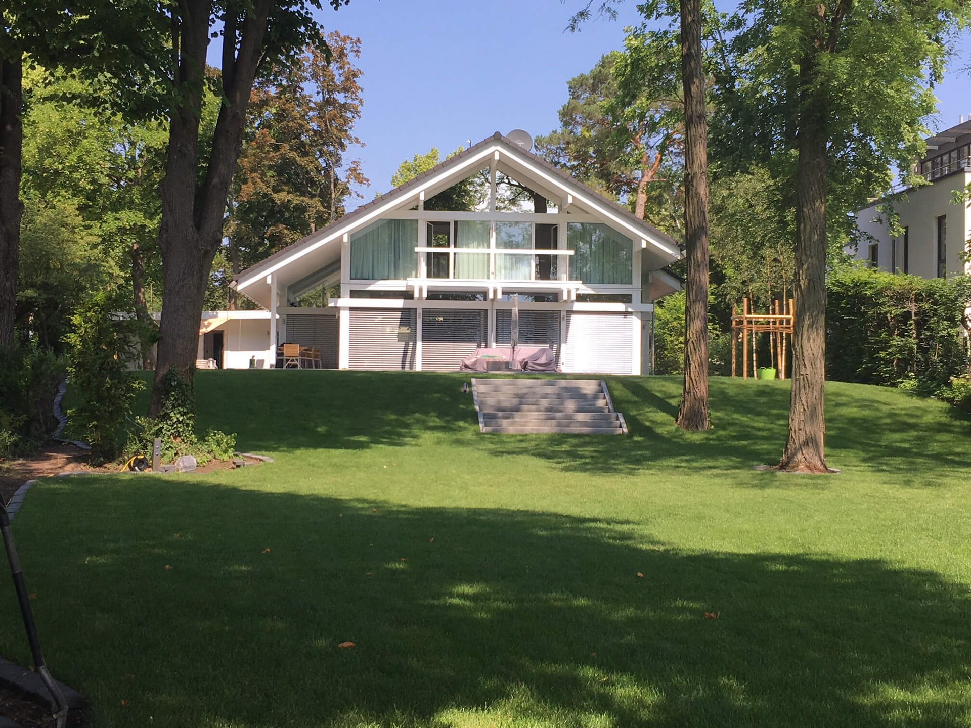 Moderne Architektur mit großzügigem Garten Haus im modernen Stil mit grünem Rasen und Bäumen im Hintergrund