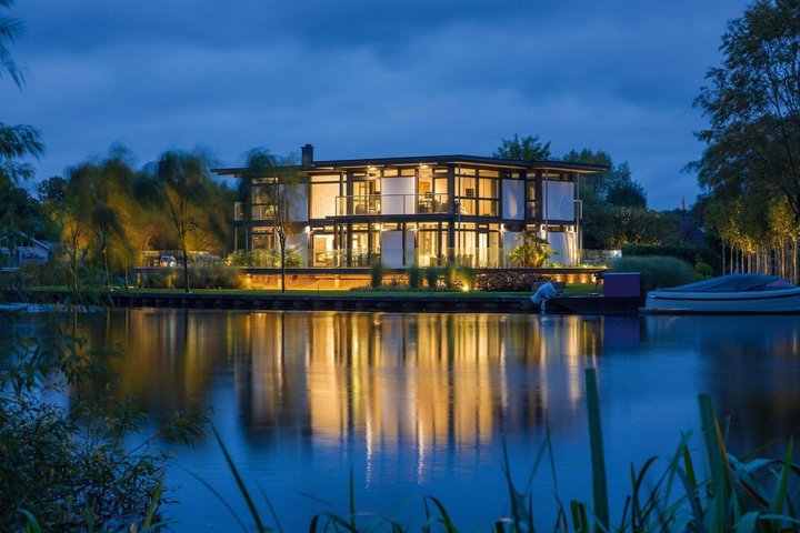 Luxushaus mit stilvollem Design und nächtlicher Beleuchtung am See