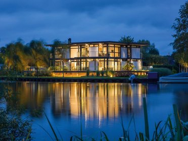Luxushaus mit stilvollem Design und nächtlicher Beleuchtung am See