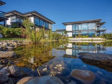 Reflektierende Bürogebäude am Wasser mit Gartenlandschaft