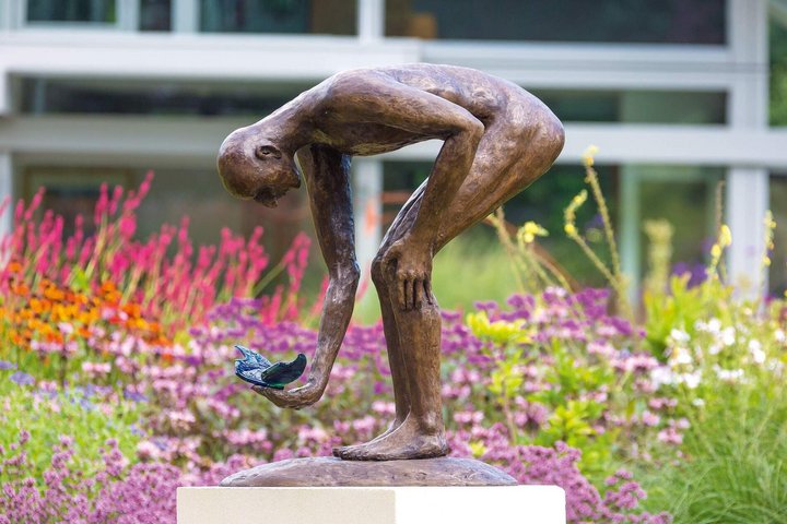 Moderne Skulptur eines Mannes in einem bunten Garten