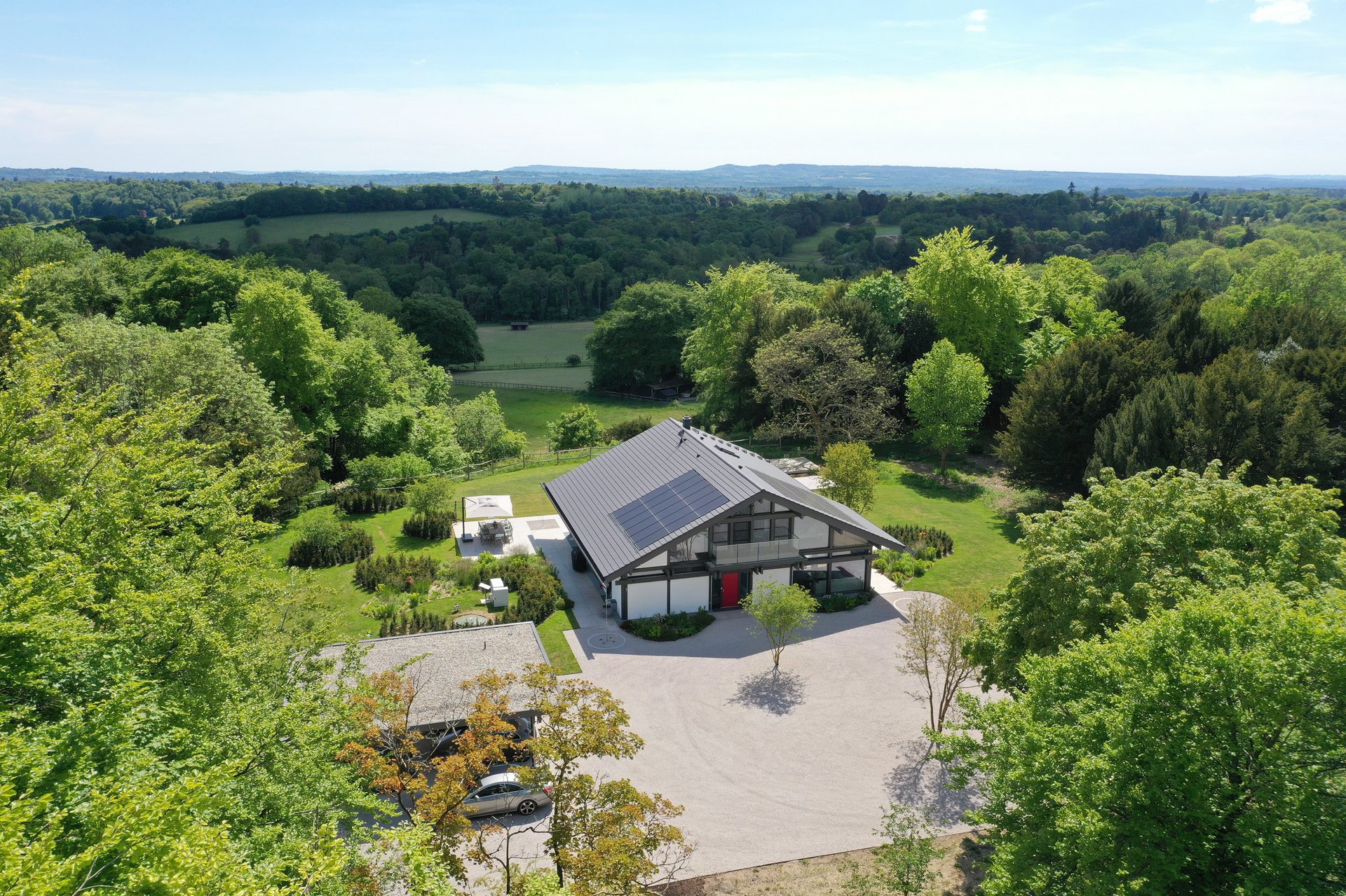 Ansicht einer modernen Villa umgeben von Bäumen und Wiesen