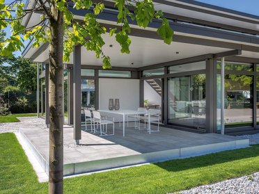 Helles Haus mit großen Fenstern und moderner Terrasse im Freien
