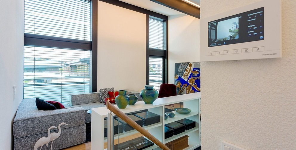 Ein heller Wohnraum mit Sofa, Dekoration und einem Steuerungssystem an der Wand