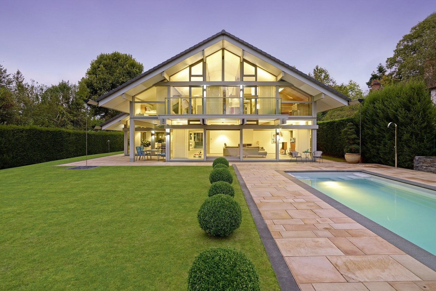 Moderne Villa mit Glasfront, Garten und Pool bei Dämmerung
