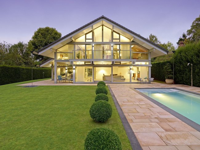 Moderne Villa mit Glasfront, Garten und Pool bei Dämmerung