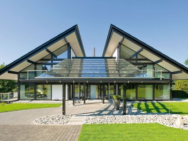 Futuristische Wohnhausfront mit begrüntem Eingangsbereich und Glas-Elementen