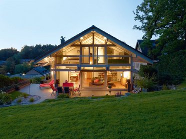 HUF Haus ART 3 grau Fachwerkhaus 11 Offene Bauweise eines HUF Hauses mit Gartenansicht bei Dämmerung
