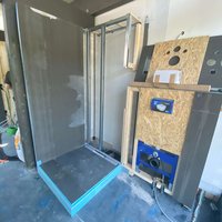 A partially installed shower with visible plumbing and structure elements.