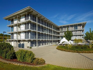 Bürogebäude HUF umgeben von Grünflächen und klaren Himmel