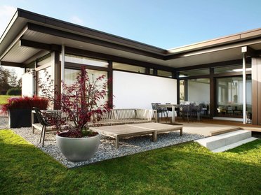 Moderne Architektur eines Bungalows mit Terrasse Bungalow mit Garten, Holzterrasse und modernen Möbeln