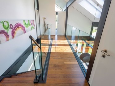 Stilvoller Flur mit Glasgeländer und Holzfußboden
