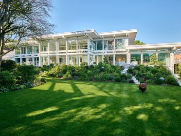 Moderne weiße Villa mit Glasfront und grünem Garten