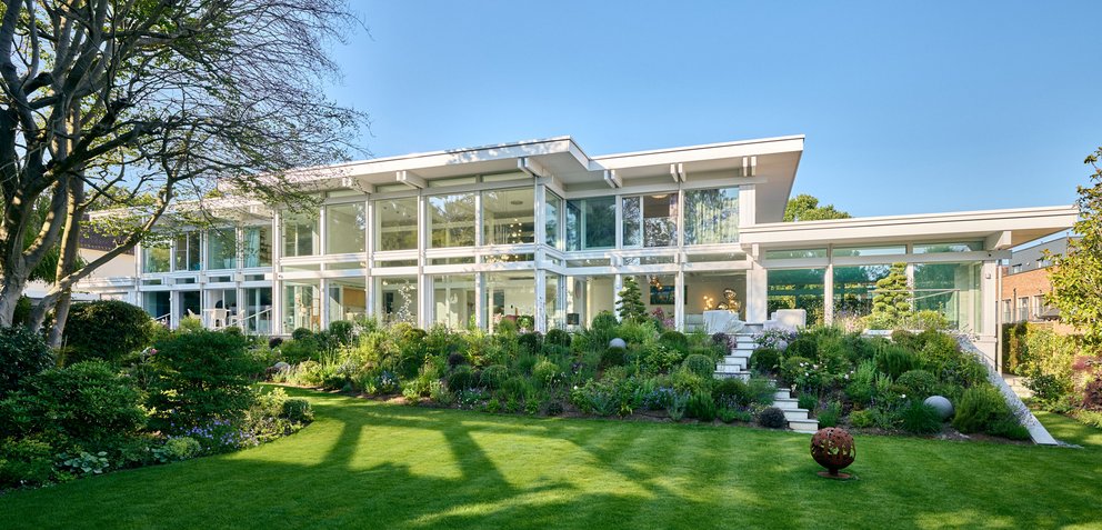 Moderne weiße Villa mit Glasfront und grünem Garten