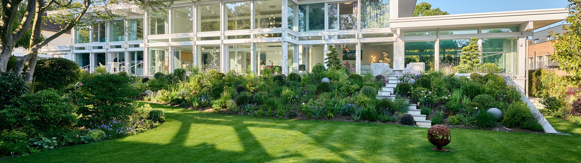 Moderne weiße Villa mit Glasfront und grünem Garten