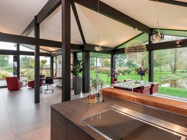 Bungalow mit organischen Formen und Glasflächen, umgeben von Bäumen und Wasserwegen.
