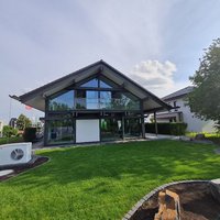 Futuristisches Gebäude mit Glasfassade und gepflegtem Garten